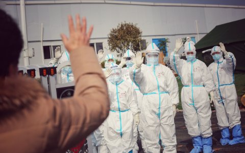 WUHAN. Un grupo de médicos hacen un gesto colectivo de saludos. Mientras más lejos, mejor.