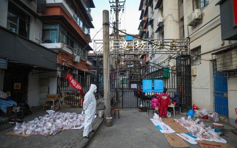 WUHAN. Un voluntario con un traje de protección, vigila una entrega de carne de cerdo para los residentes en cuarentena en un barrio de esta ciudad china.