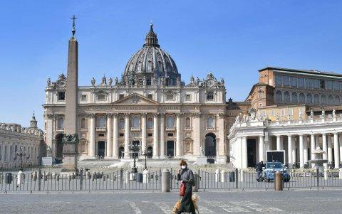 ROMA. Una mujer atraviesa la Plaza San Pedro, con unas cuantas personas transitándola en estos días de cuarentena.
