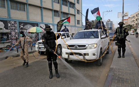 GAZA. Brigadas de las fuerzas palestinas recorren una avenida para desinfectar  el sector, como medida de prevención por el coronavirus.