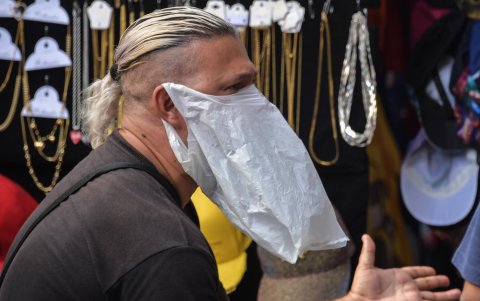 SAO PAULO, BRASIL:  Un vendedor informal usa una funda de plástico por prevención.