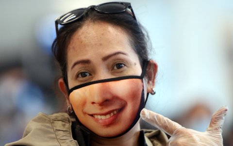 MANILA, FILIPiNAS: Una mujer muestra su máscara con una sonrisa estampada.