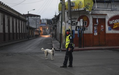 AMATITLÁN, GUATEMALA: Un oficial de policía usa una máscara junto a un perro en una calle vacía durante un toque de queda parcial ordenado por el gobierno.