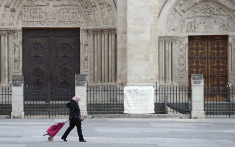 SAINT-DENIS, FRANCIA: Una mujer que lleva una máscara protectora pasa por la Basílica el 2 de abril de 2020, en el día diecisiete de encierro.