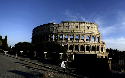 ROMA, ITALIA: Una mujer camina con su perro por el Coliseo, durante el cierre del país.