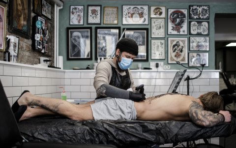 COPENHAGUE. Usando mascarilla, el artista Ruben trabaja un tatuaje. Dinamarca comenzó a aliviar las restricciones para los negocios locales después del bloqueo por la pandemia de COVID-19.