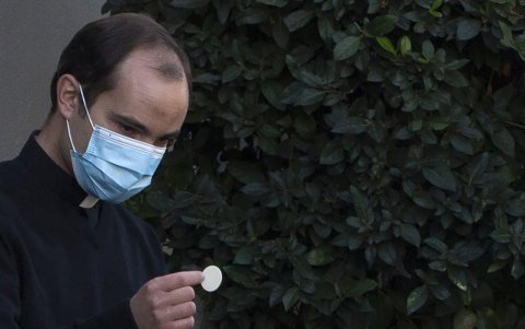 Un sacerdote católico da la comunión en los exteriores de la iglesia de San Francisco de Asís, en Santiago