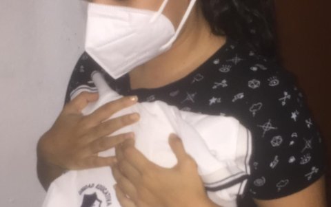 Una alumna de la Unidad Educativa de Santa Luisa de Marillac llora abrazando su uniforme tras enterarse de que la entidad fue cerrada. En su casa su padre aún está en proceso de curarse del COVID-19.