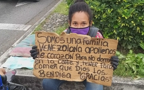 Una ciudadana venezolana muestra un cartel que usa para pedir ayuda.