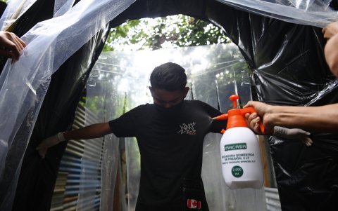 Jóvenes de la comunidad de Tineti desinfectan a los vecinos cuando ingresan a la ciudad, en San Salvador, como medida de protección contra el coronavirus.
