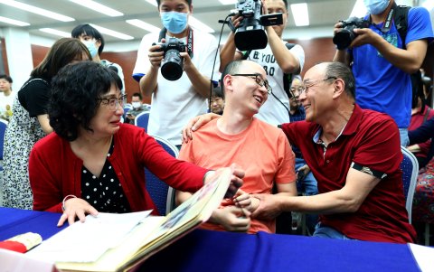 Mao Yin (C) junto a su madre Li Jingzhi y su padre Mao Zhenping revisan archivos de fotos de la familia
