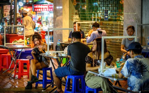 BANGKOK. Varias personas comen en un restaurante callejero que implementa el distanciamiento social con divisores de plástico.