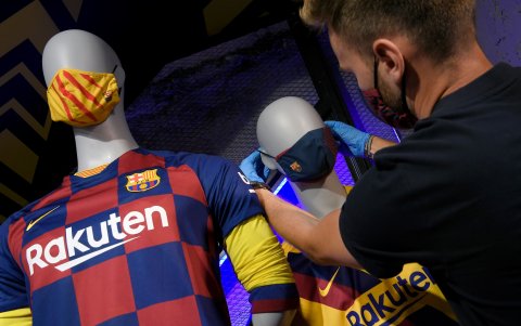 El trabajador de una de las tiendas oficiales del Barcelona de España arregla en un maniquí una de las mascarillas que el equipo lanzó a la venta desde hoy.