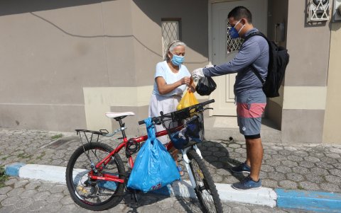 Enrique Bravo entrega el mandado a una de sus vecinas de la tercera edad, en Samanes. Él, para movilizarse, utiliza una bicicleta, así puede salir a ayudar todos los días.
