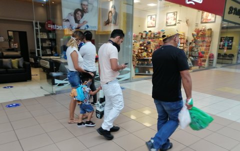 En un centro comercial hasta un niño lleva puesta la mascarilla, pero el adulto se la ha dejado de adorno en el cuello.