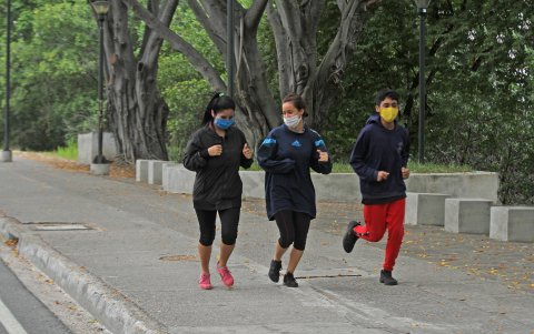 En Guayaquil, tres jóvenes hacen ejercicio al aire libre usando mascarillas.