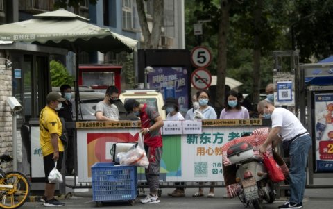 Varias personas con mascarilla esperan la entrega de productos comprados.