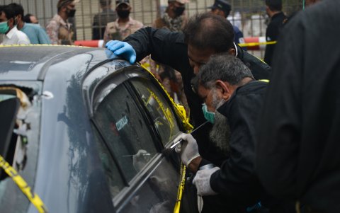 KARACHI. Miembros de la Unidad de Escena del Crimen de la Policía recogen huellas del automóvil usado por los pistoleros en la entrada principal del edificio de la Bolsa de Valores.