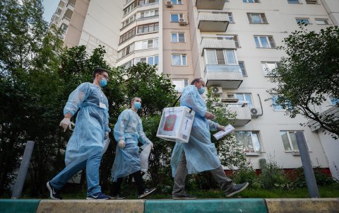 MOSCÚ. Una comisión electoral local, vestidos con trajes protectores, trasladan una urna portátil, en busca de electores. Es una opción para los rusos que no pueden dejar sus casas.