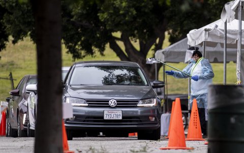 LOS ÁNGELES. Un voluntario le entrega a un conductor una prueba autoadministrada para COVID-19 en un sitio de prueba de entrada y salida en Lincoln Park.