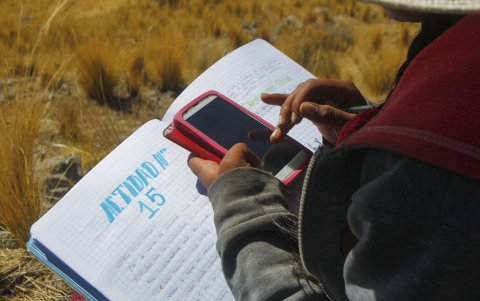 Roxana Cabrera, de 16 años, toma notas durante una clase virtual desde la cima de una colina desde donde ella y sus hermanos pueden recibir señal en sus teléfonos móviles