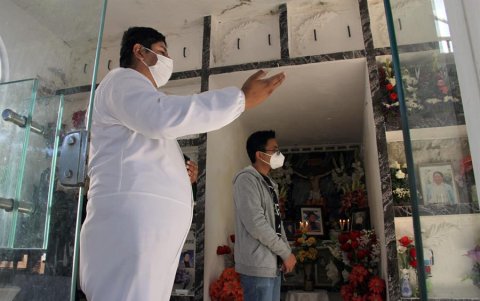 Rolando Loayza realiza su labor de rezar con traje blanco de bioseguridad.