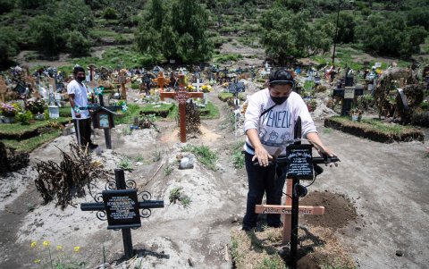 SAN MIGUEL XICO. Una mujer arregla una cruz en un cementerio en este pueblo mexicano. Visita a un pariente, víctima reciente de la pandemia.