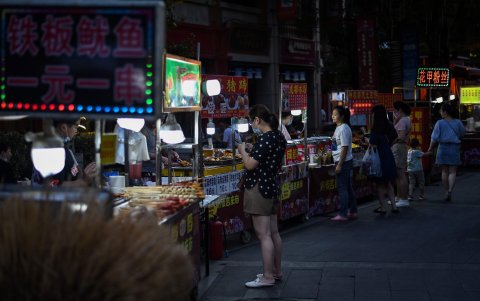 WUHAN. Unas cuantas personas buscan comidas en uno puesto callejero. Las ventas comenzaron a subir con la vuelta a la normalidad.