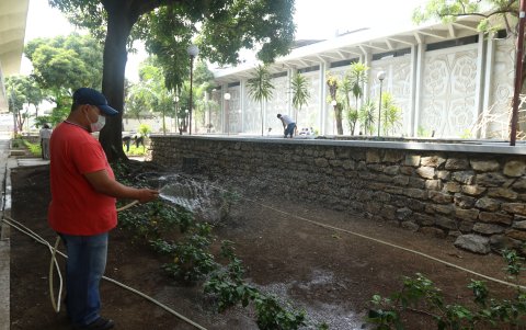 Trabajadores de la Facultad de Arquitectura riegan las plantas que han sembrado en las jardineras.