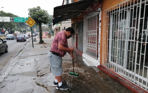 Sergio Olvera, dueño de una peluquería en Pradera 2, retira el agua que sale por una fuga que se dio.