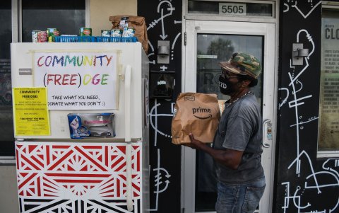 MIAMI. Theotis Stacy, de 64 años, toma comida gratis de un refrigerador comunitario. Sherina Jones, instaló el frigorífico en el vecindario para las personas pobres.