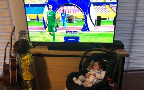 Los hijos del arquero camarata frente al televisor.