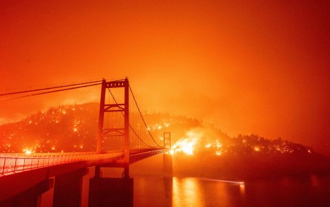 Lake Oroville. Un barco cruza una área aledaña al puente Bidwell Bar, mientras se observan los diferentes puntos en los que arde el bosque.