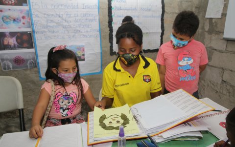 La bachiller Nikol Rosero ayuda a los niños del sector Las Cumbres a preparar el portafolio de tareas escolares. Ella los recibe en su vivienda.