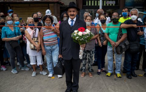 Un hombre disfrazado de José Gregorio Hernández saluda a un grupo de personas durante la exhumación de los restos de religioso hoy, en las inmediaciones de la iglesia de Nuestra Señora de La Candelaria.