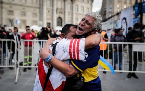 Un hincha de River Plate y otro de Boca Juniors se abrazan y lloran por la partida de Diego Maradona.