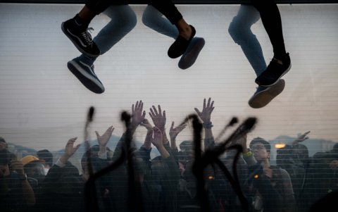 Un grupo de manifestantes colgado de un puente mientras otros los apoyan desde abajo.