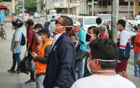 Un grupo de personas hacen fila en las afueras de una farmacia para comprar medicinas.