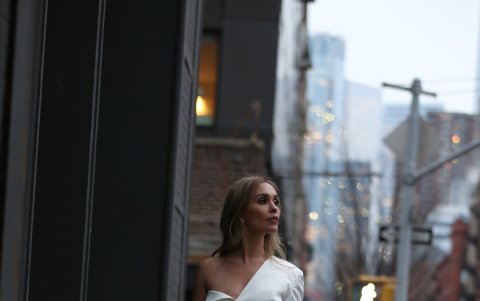Fernanda Cobo en un mini vestido blanco, con zapatos y cartera negra.