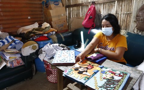 Denisses Toala, líder comunitaria, revisa los portafolios escolares de los niños que recibe en el patio de su casa.