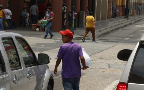 Un vendedor informal camina entre los carros pero observa hacia el interior del automotor lo que asusta a los pasajeros y conductor.