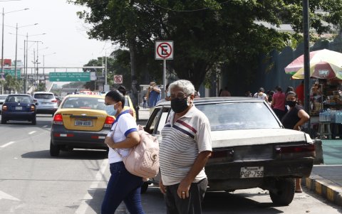 Una persona de la tercera edad espera cruzar la calle en la avenida 25 de Julio, por el hospital del Día Valdivia, del IESS; está la luz roja pero los carros invaden la zona cebra.