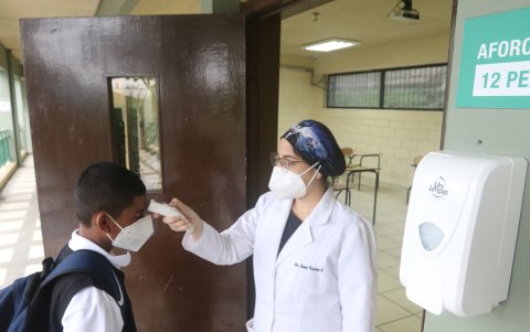 Para entrar a la institución y a las aulas, la doctora Nancy Palacios, del colegio Delfos, toma la temperatura a quienes asisten a la jornada presencial.