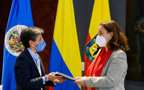 La alcaldesa Claudia López (izq.) y la comisionada de la CIDH, Antonia Urrejola (der.), intercambian informes durante una ceremonia.