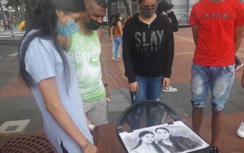 Una familia observa el retrato hecho a dos de sus integrantes en el Malecón 2000.