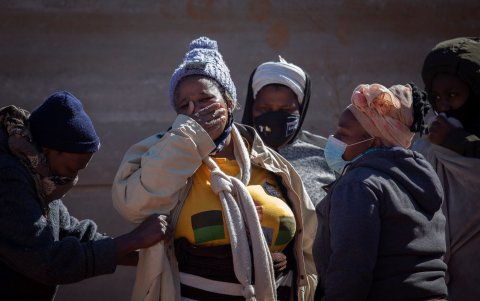 Los familiares de uno de los dos saqueadores fallecidos lloran junto a su cuerpo después de su muerte tras saquear productos de las tiendas de la zona, Johannesburgo, Sudáfrica, el 13 de julio de 2021.