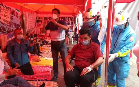 Paramédicos del Cuerpo de Bomberos conducen al maestro Pedro Delgado hasta una ambulancia para ser llevado a un hospital.