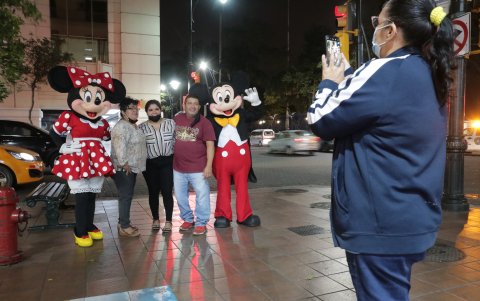 Una mujer toma fotos a su familia con los personajes de Disney, representados por una pareja de venezolanos.