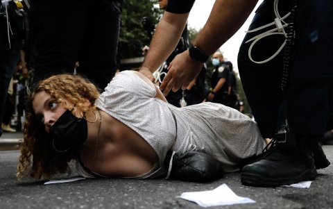 Una mujer es inmovilizada y detenida por la policía.
