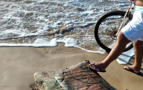 Una persona apoya un pie sobre un bulto arrojado por el mar.